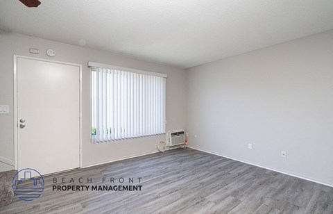 a living room with wood flooring and white walls and a window